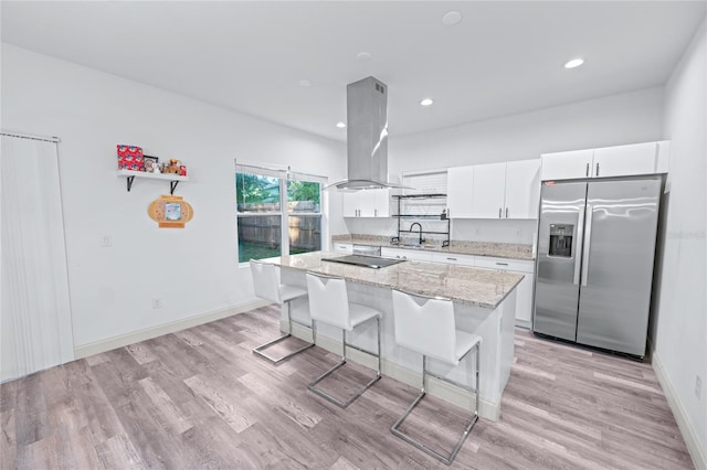 kitchen with white cabinets, island exhaust hood, light wood-type flooring, and stainless steel fridge with ice dispenser