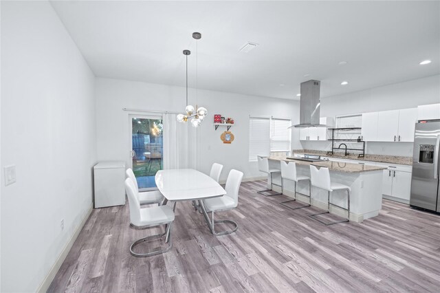 dining area with light wood-type flooring, a chandelier, and sink