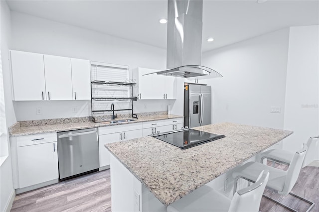 kitchen with white cabinets, sink, island range hood, appliances with stainless steel finishes, and light wood-type flooring