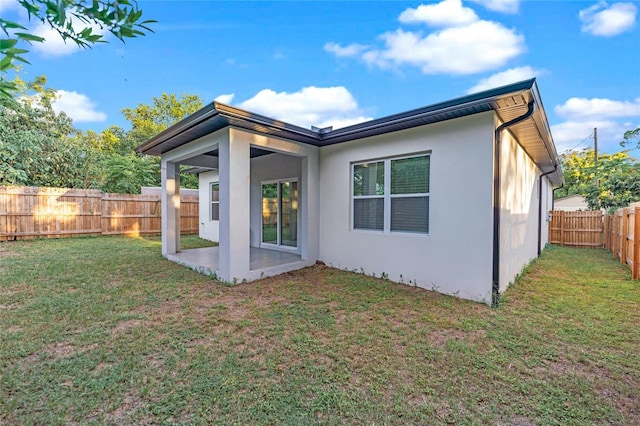 rear view of house featuring a yard and a patio