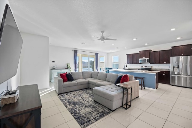 tiled living room featuring ceiling fan, a textured ceiling, and sink