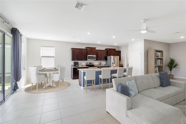 living room featuring sink, light tile patterned floors, and ceiling fan