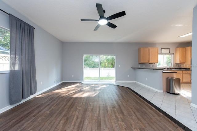 unfurnished living room featuring light hardwood / wood-style flooring, ceiling fan, and sink