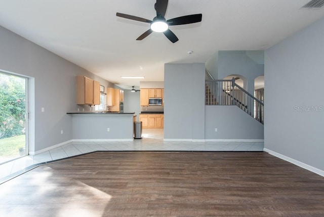 unfurnished living room featuring ceiling fan and hardwood / wood-style flooring