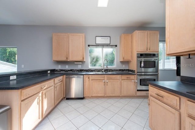 kitchen featuring stainless steel appliances, light brown cabinetry, a healthy amount of sunlight, and sink