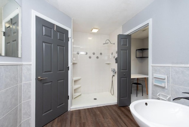 bathroom featuring tile walls, hardwood / wood-style floors, and tiled shower