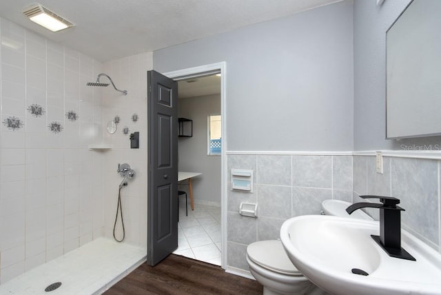 bathroom with tiled shower, toilet, hardwood / wood-style flooring, and sink