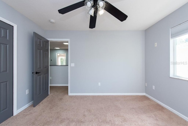 carpeted empty room with a healthy amount of sunlight and ceiling fan