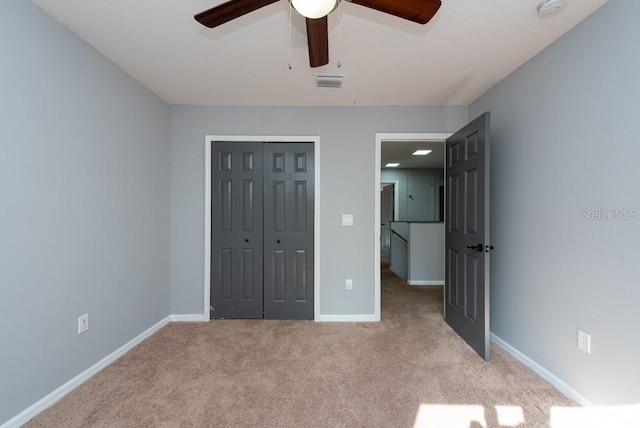 unfurnished bedroom with light carpet, ceiling fan, and a closet