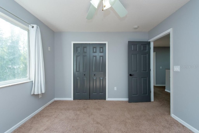 unfurnished bedroom featuring light carpet, a closet, and ceiling fan