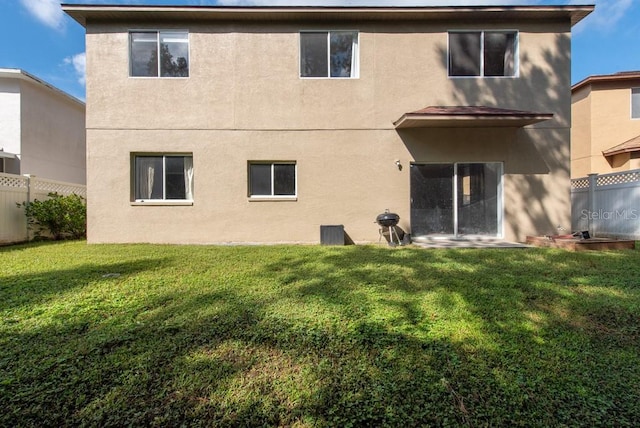 back of property with a lawn and a patio