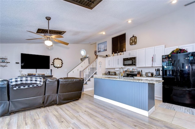 kitchen with black appliances, light hardwood / wood-style flooring, and white cabinets