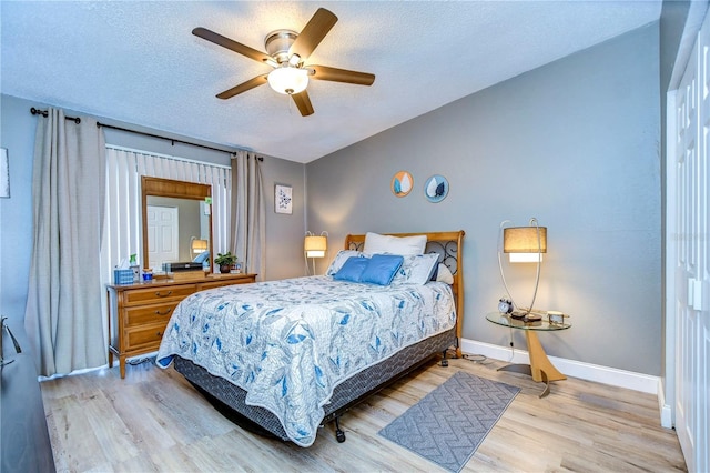 bedroom with a textured ceiling, light hardwood / wood-style floors, and ceiling fan