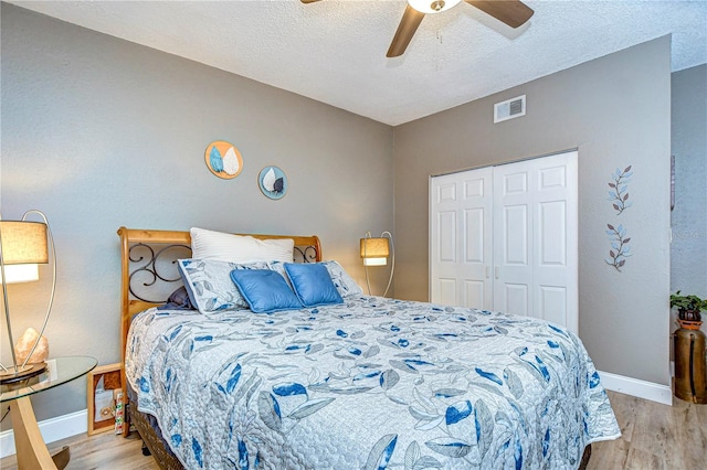 bedroom with light wood-type flooring, a textured ceiling, ceiling fan, and a closet