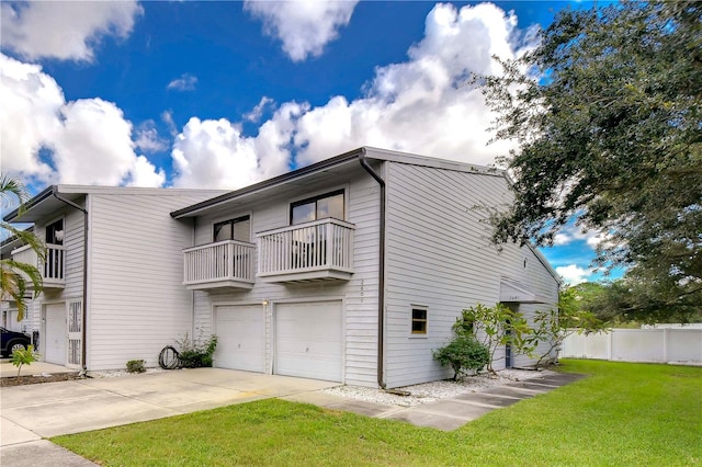 rear view of house with a balcony, a lawn, and a garage