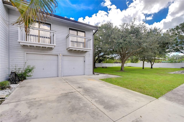 view of side of property with a balcony, a yard, and a garage