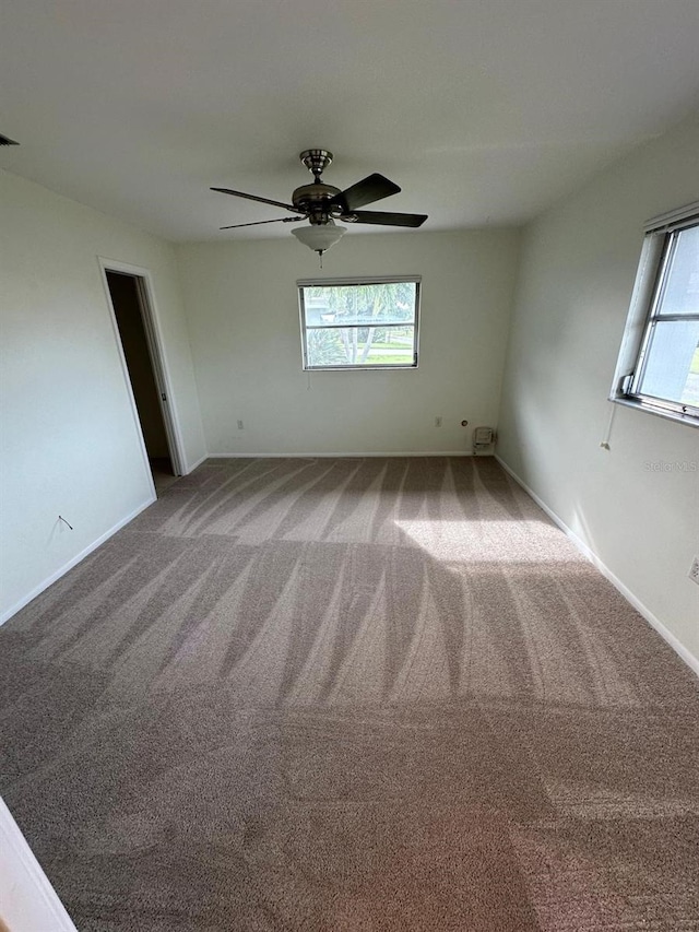 carpeted empty room with a wealth of natural light and ceiling fan