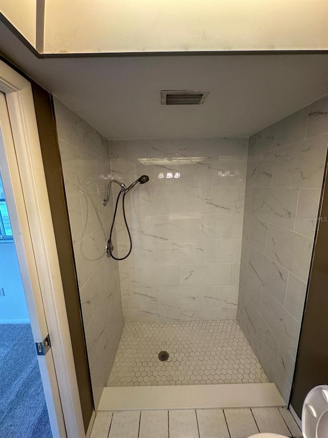 bathroom with tile patterned flooring and tiled shower