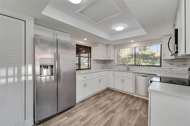 kitchen with white cabinets, appliances with stainless steel finishes, and a raised ceiling