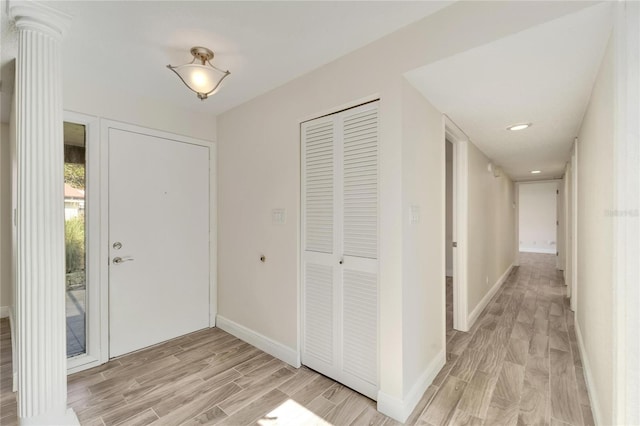 foyer featuring light wood-type flooring and decorative columns