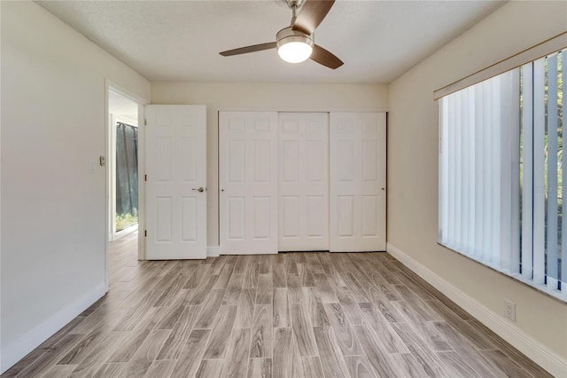 unfurnished bedroom with light wood-type flooring, ceiling fan, and a closet