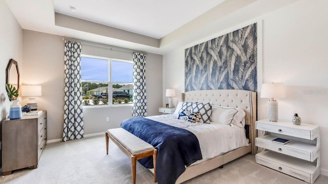 bedroom featuring light carpet and a tray ceiling