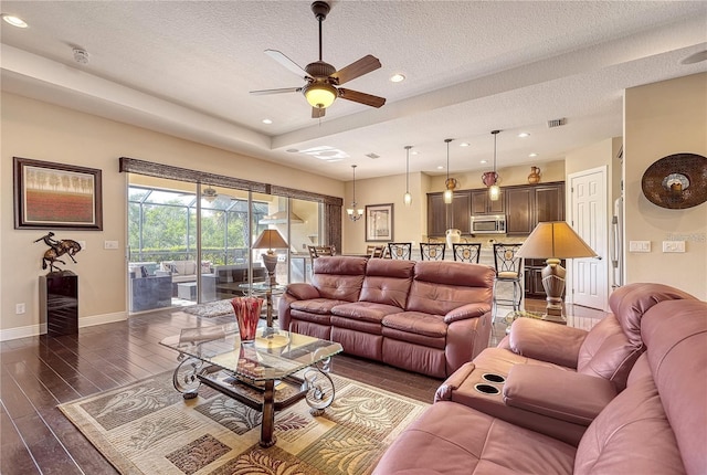 living room featuring ceiling fan, a textured ceiling, and dark wood-type flooring