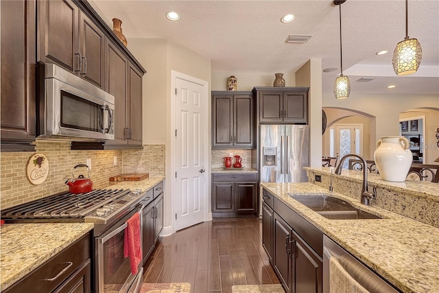 kitchen featuring pendant lighting, a textured ceiling, appliances with stainless steel finishes, and sink