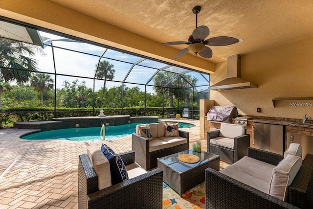 view of swimming pool featuring a lanai, an outdoor kitchen, sink, a patio area, and ceiling fan