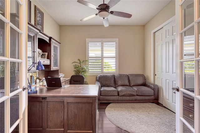 office space featuring a healthy amount of sunlight, dark hardwood / wood-style floors, ceiling fan, and french doors