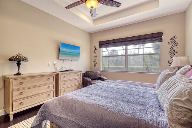 bedroom featuring ceiling fan, a raised ceiling, and dark hardwood / wood-style floors