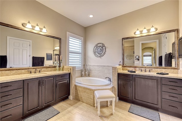 bathroom featuring vanity, a relaxing tiled tub, and tile patterned floors