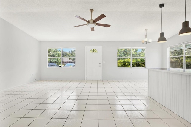 tiled spare room featuring ceiling fan with notable chandelier