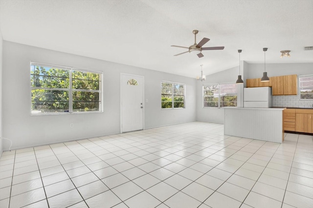 unfurnished living room with a wealth of natural light, light tile patterned floors, and lofted ceiling