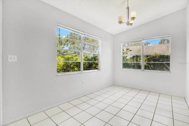 spare room featuring plenty of natural light, an inviting chandelier, light tile patterned floors, and vaulted ceiling