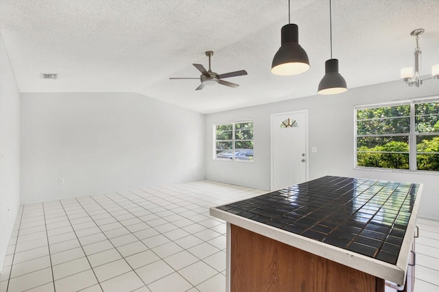 kitchen with ceiling fan with notable chandelier, lofted ceiling, hanging light fixtures, and a wealth of natural light