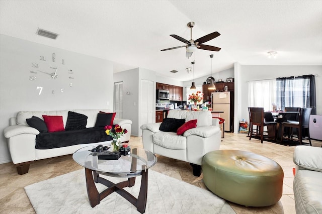 living room with ceiling fan, a textured ceiling, and vaulted ceiling