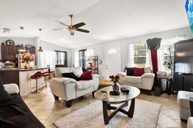 living room with a textured ceiling, ceiling fan, and lofted ceiling