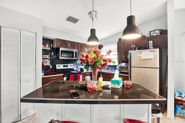 kitchen with backsplash, stainless steel appliances, pendant lighting, a kitchen island, and a breakfast bar area