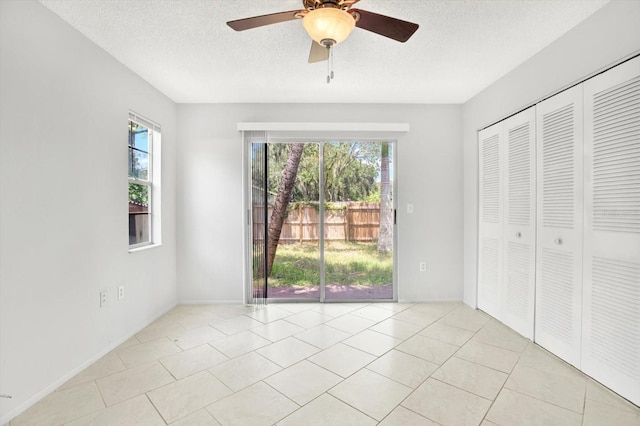 unfurnished bedroom featuring ceiling fan, a closet, light tile patterned floors, and multiple windows