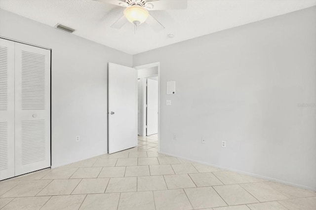 unfurnished bedroom with ceiling fan, light tile patterned floors, and a closet