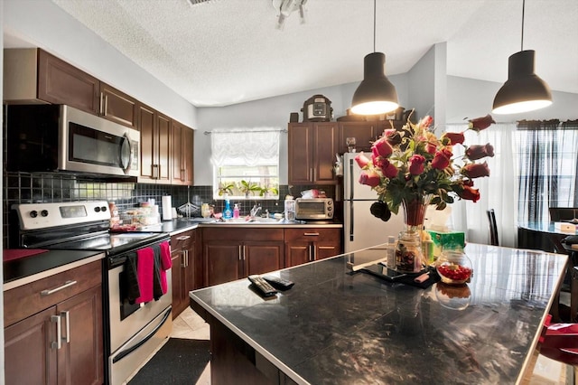 kitchen with pendant lighting, a textured ceiling, appliances with stainless steel finishes, tasteful backsplash, and a kitchen island