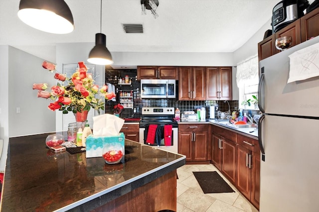 kitchen featuring backsplash, stainless steel appliances, sink, light tile patterned floors, and decorative light fixtures