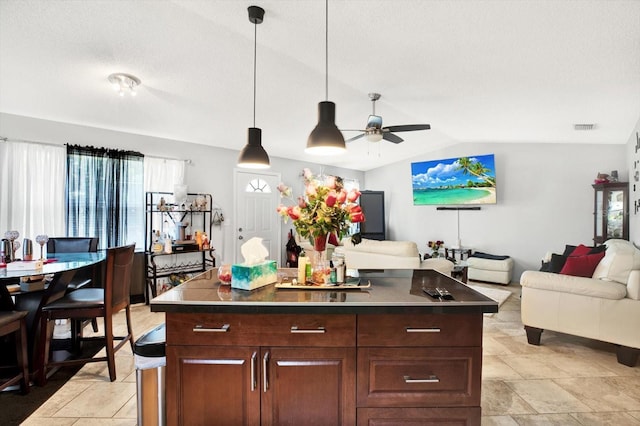 kitchen featuring ceiling fan, a center island, lofted ceiling, and a textured ceiling