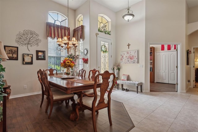 dining room with a towering ceiling, light hardwood / wood-style floors, and a chandelier