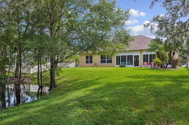 back of property with a sunroom and a lawn