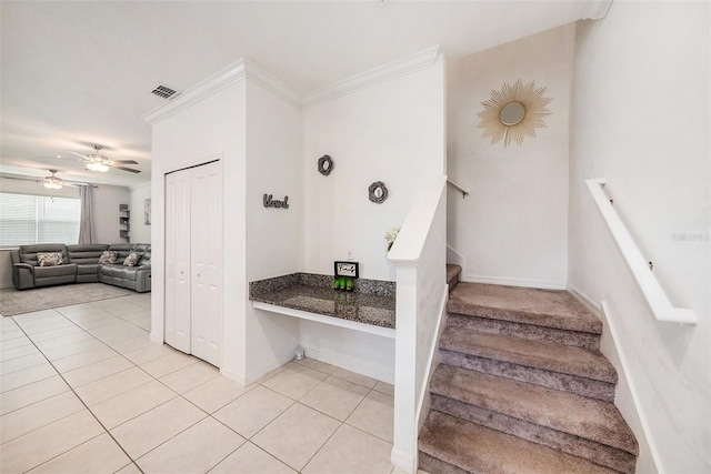 stairs featuring tile patterned flooring, ceiling fan, and crown molding