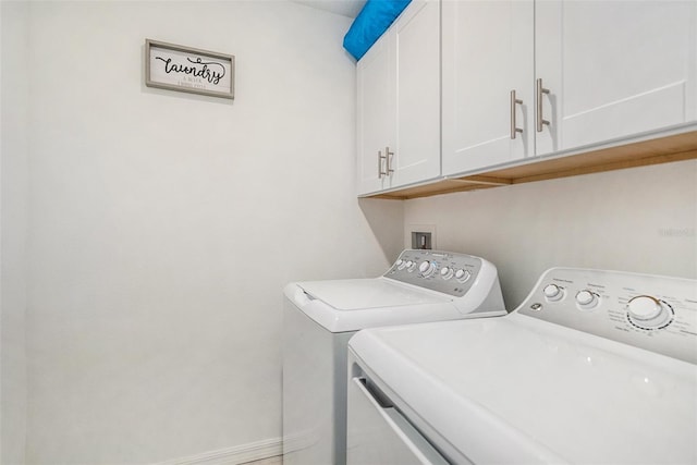 clothes washing area featuring separate washer and dryer and cabinets