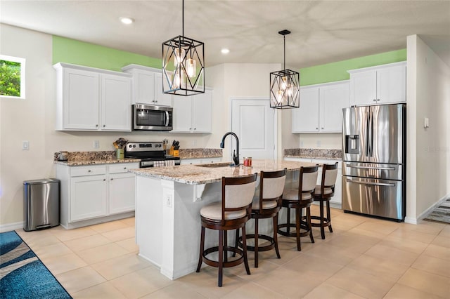 kitchen featuring white cabinetry, sink, stainless steel appliances, and a center island with sink