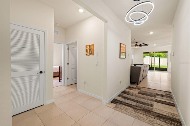 corridor featuring light tile patterned floors and a chandelier